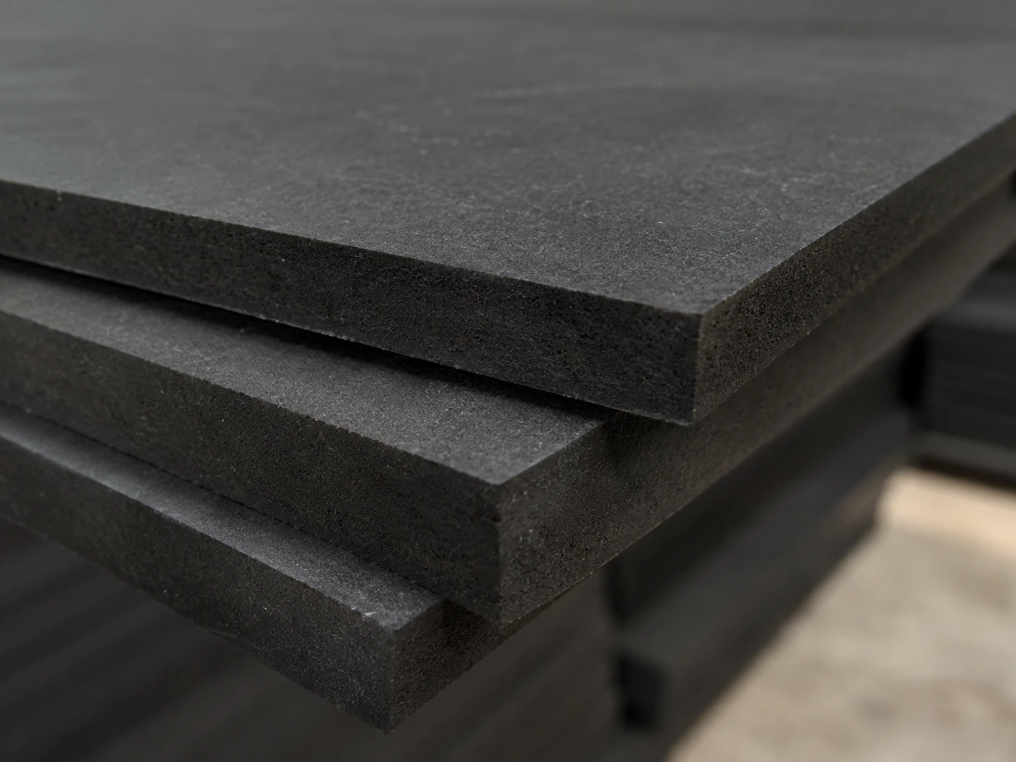 Stacked black MDF panels showing faces and cut edges