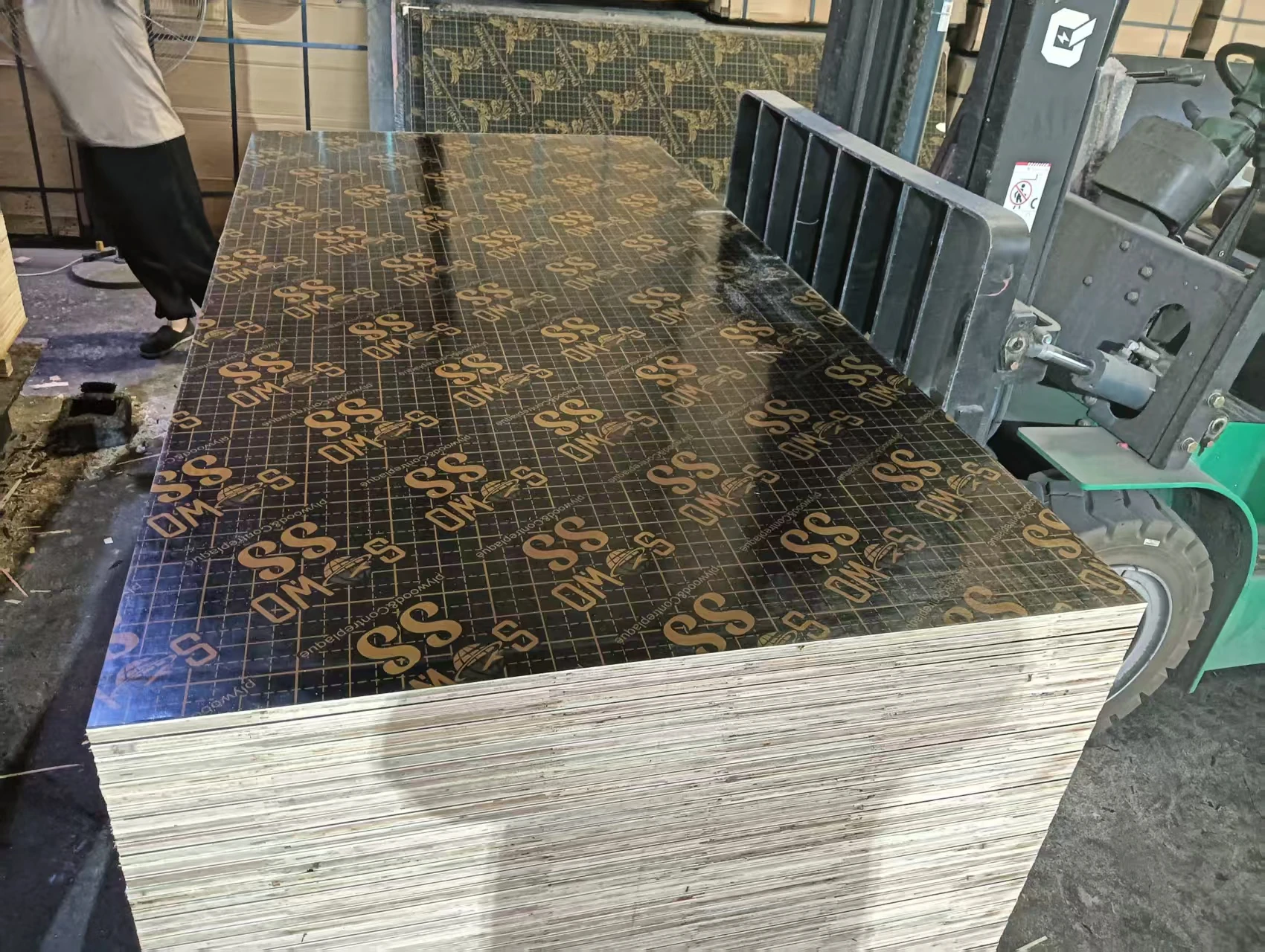 SOWO-branded film faced plywood stack beside a forklift